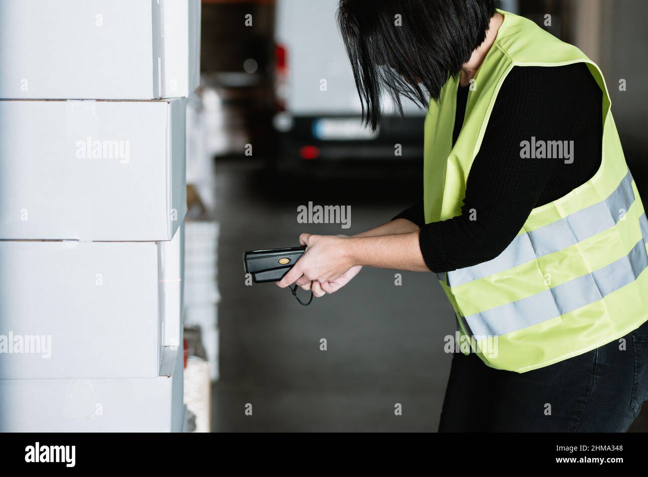Side view of crop anonymous female warehouse worker in green 