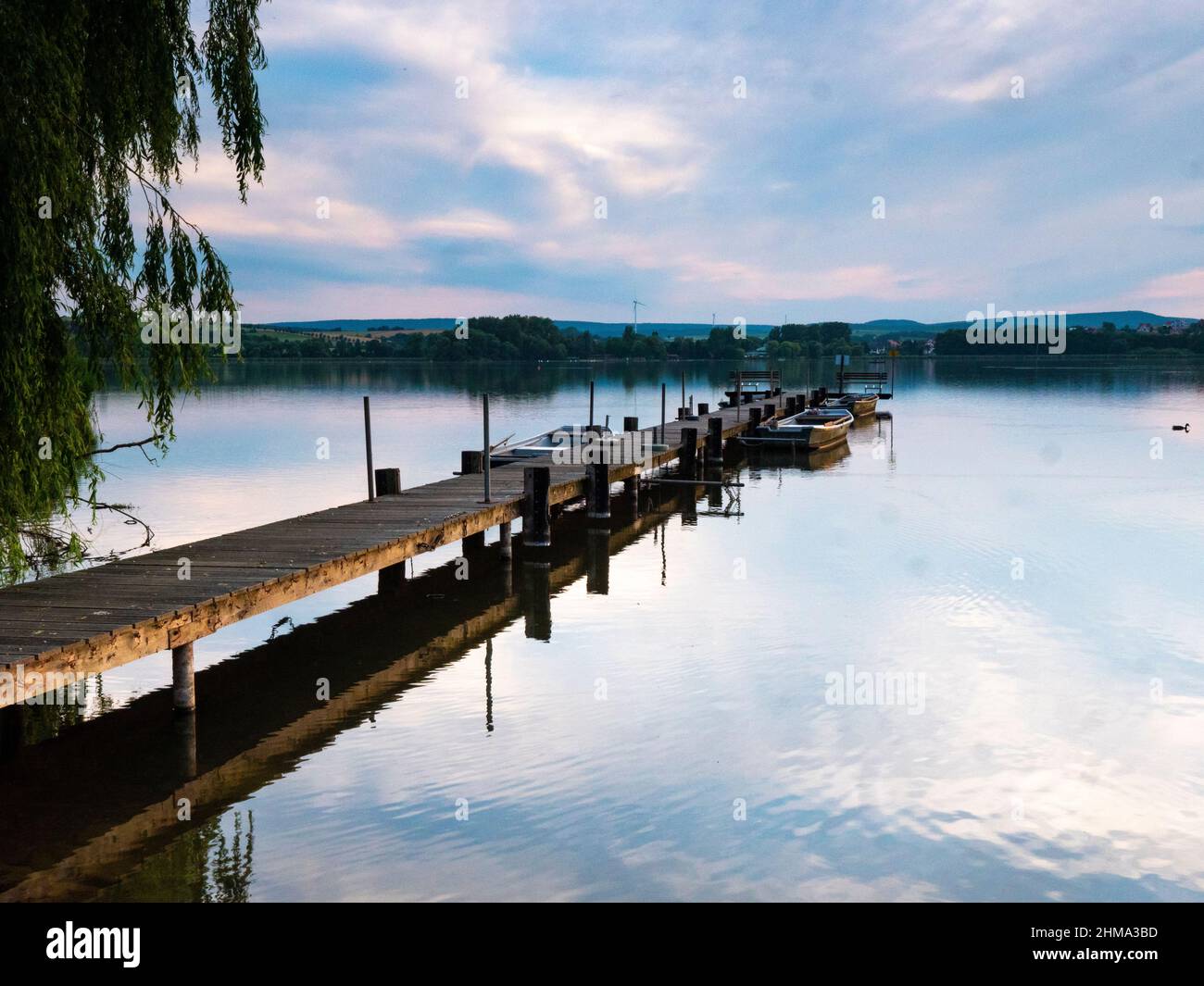 A long landing stage with a few rowing boats in the evening mood Stock Photo