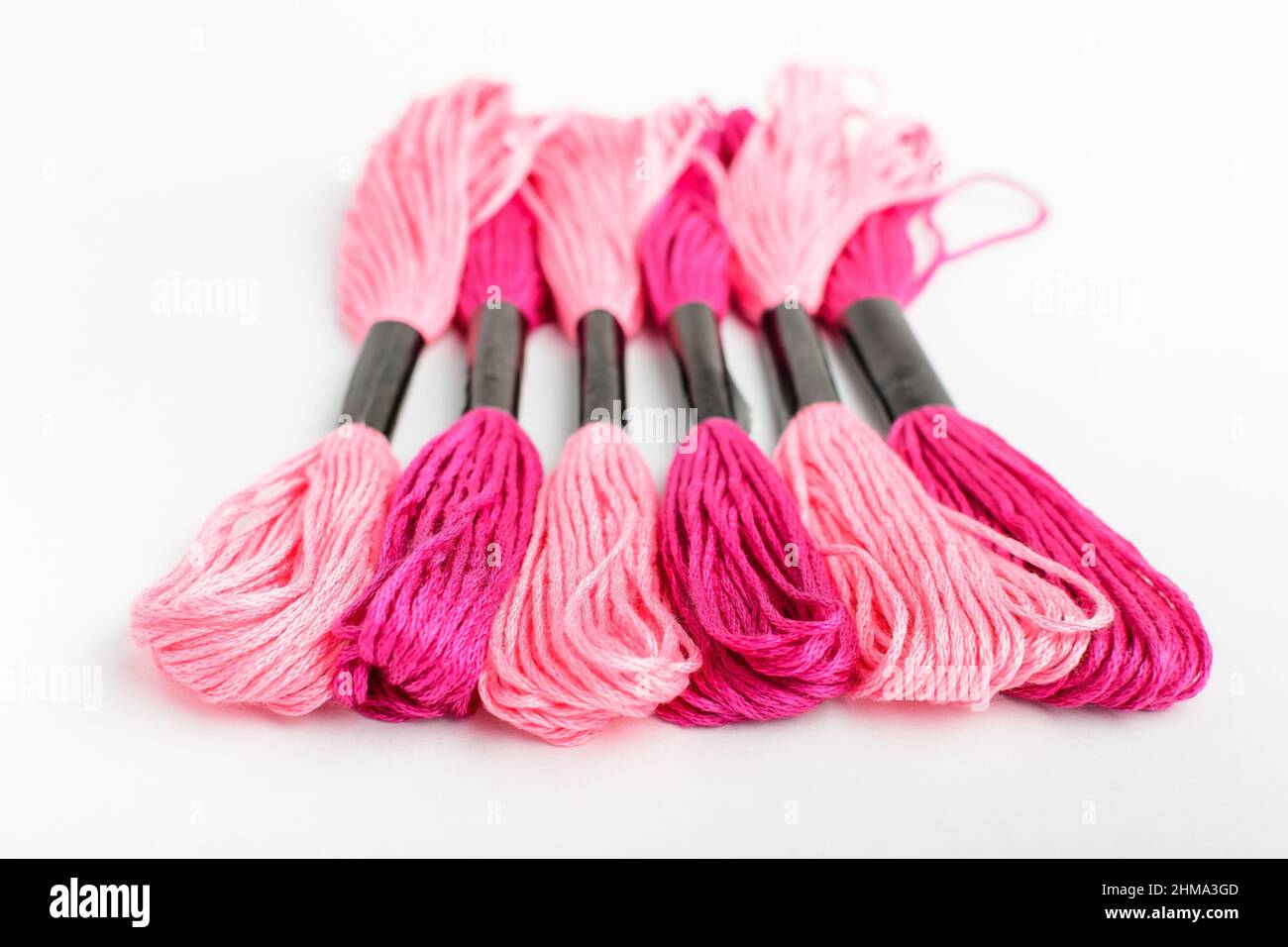 Five vivid pink sewing threads for embroidery isolated on a white table ...