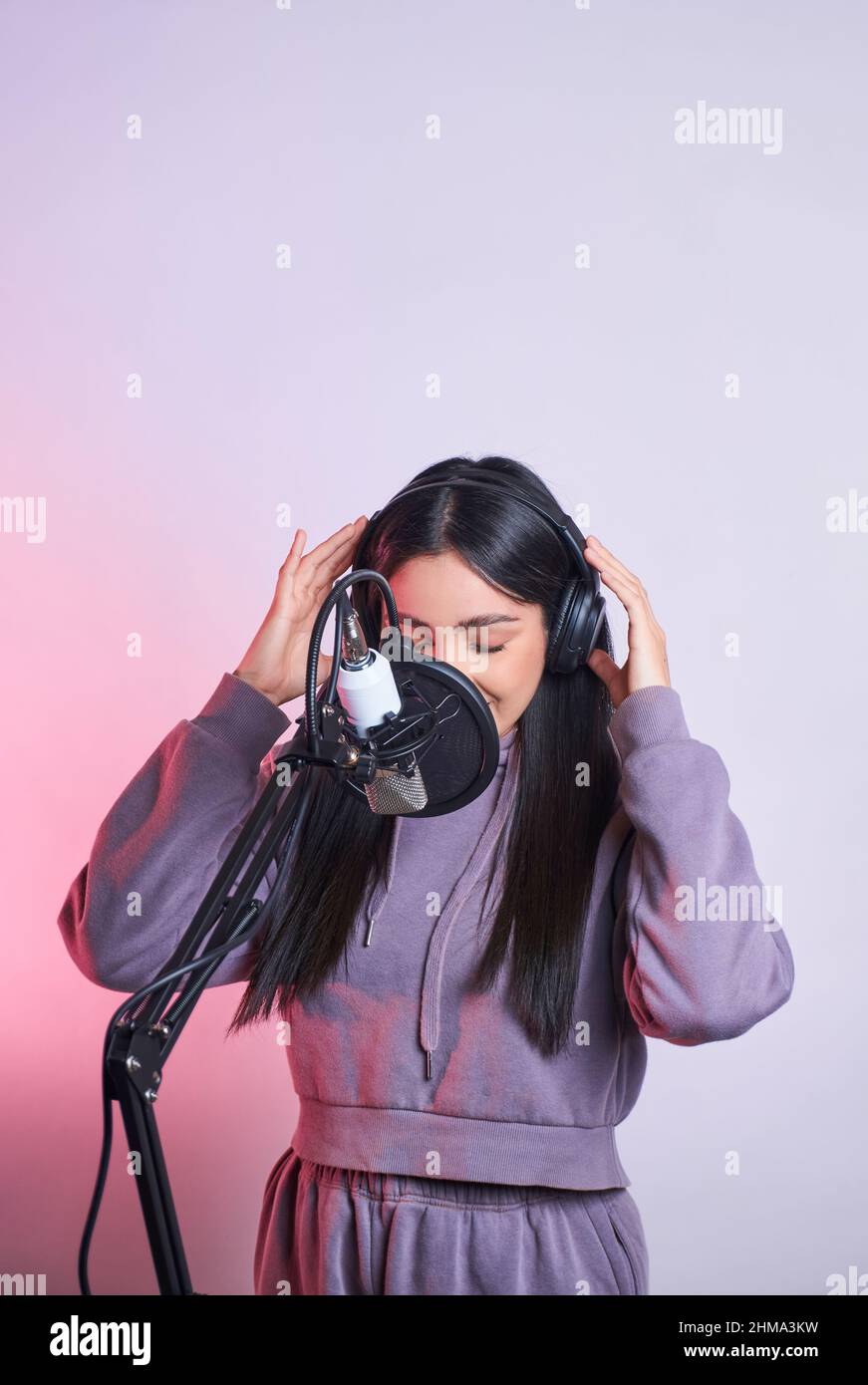 Young talented female casual wear and headphones singing into