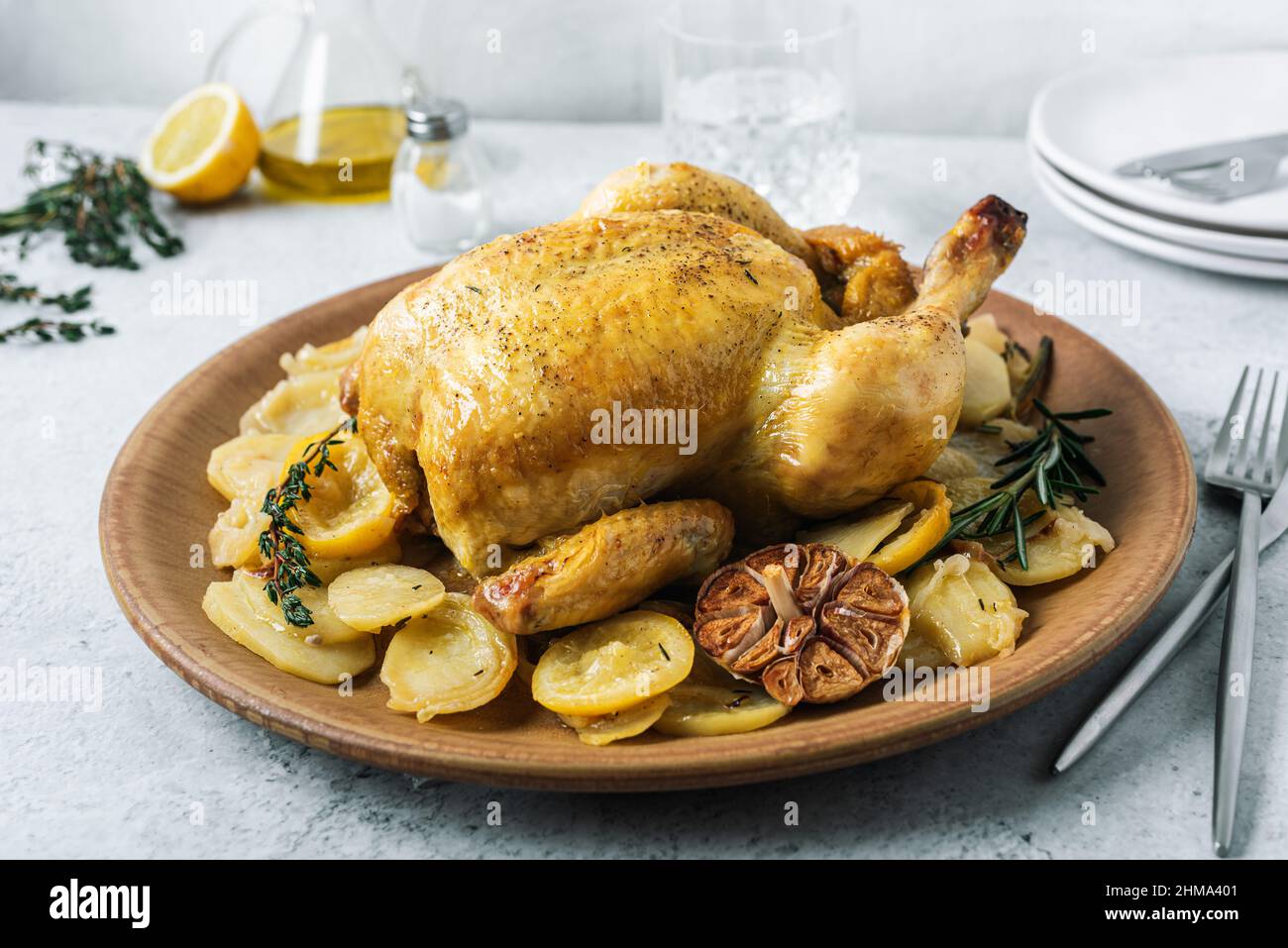 From above of ceramic plate with roasted chicken garnished with slices of roasted potatoes and seasoned with fresh rosemary and different spices Stock Photo