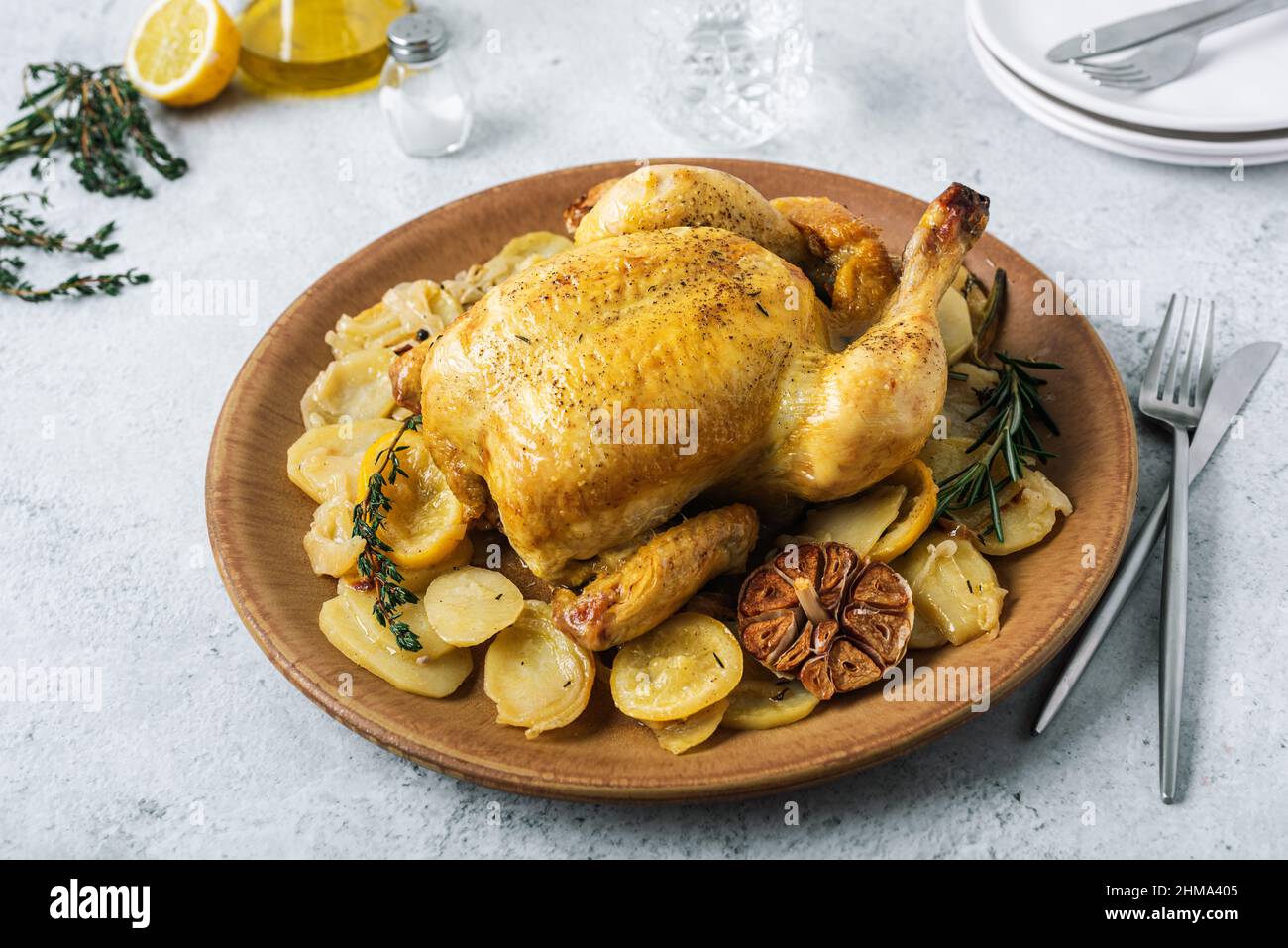 From above of ceramic plate with roasted chicken garnished with slices of roasted potatoes and seasoned with fresh rosemary and different spices Stock Photo