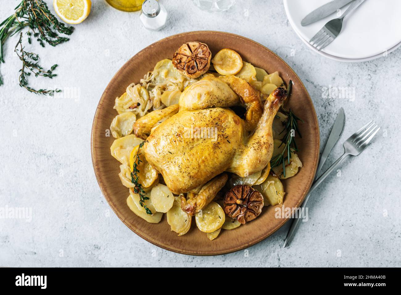 From above of ceramic plate with roasted chicken garnished with slices of roasted potatoes and seasoned with fresh rosemary and different spices Stock Photo