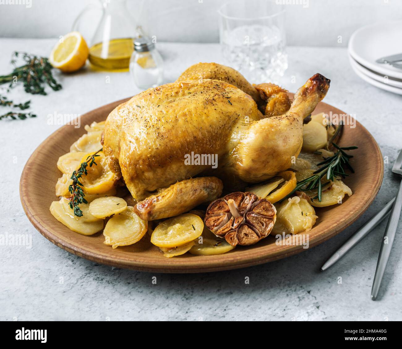 From above of ceramic plate with roasted chicken garnished with slices of roasted potatoes and seasoned with fresh rosemary and different spices Stock Photo