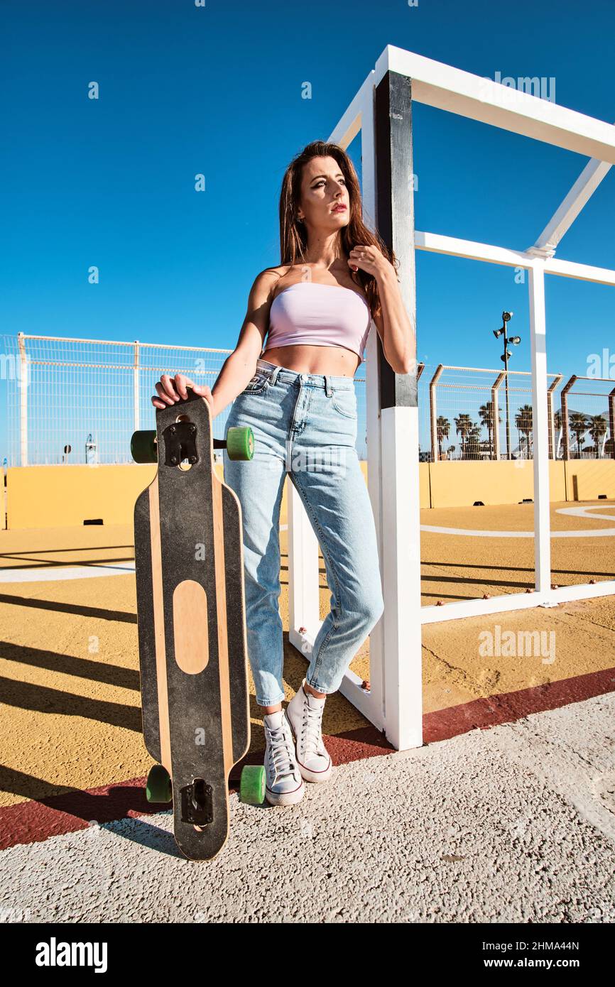 Full length of slim confident young brunette in jeans and top standing ...