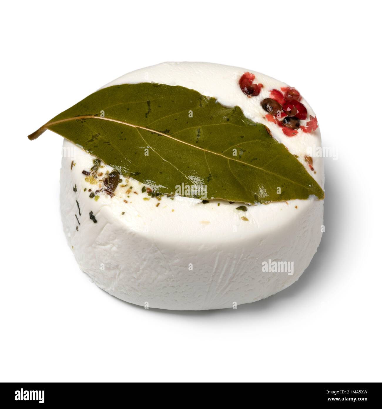 Single French goat cheese with herbs, bay laurel, red peppercorns and olive oil, Tomette provencal a l'huile, isolated on white background Stock Photo