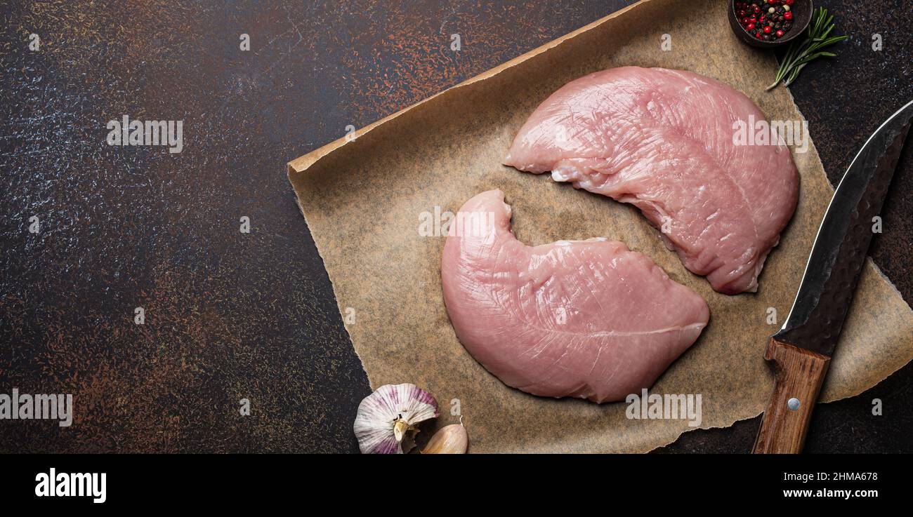 Turkey lean raw fillet on baking paper with rosemary, garlic and spices Stock Photo