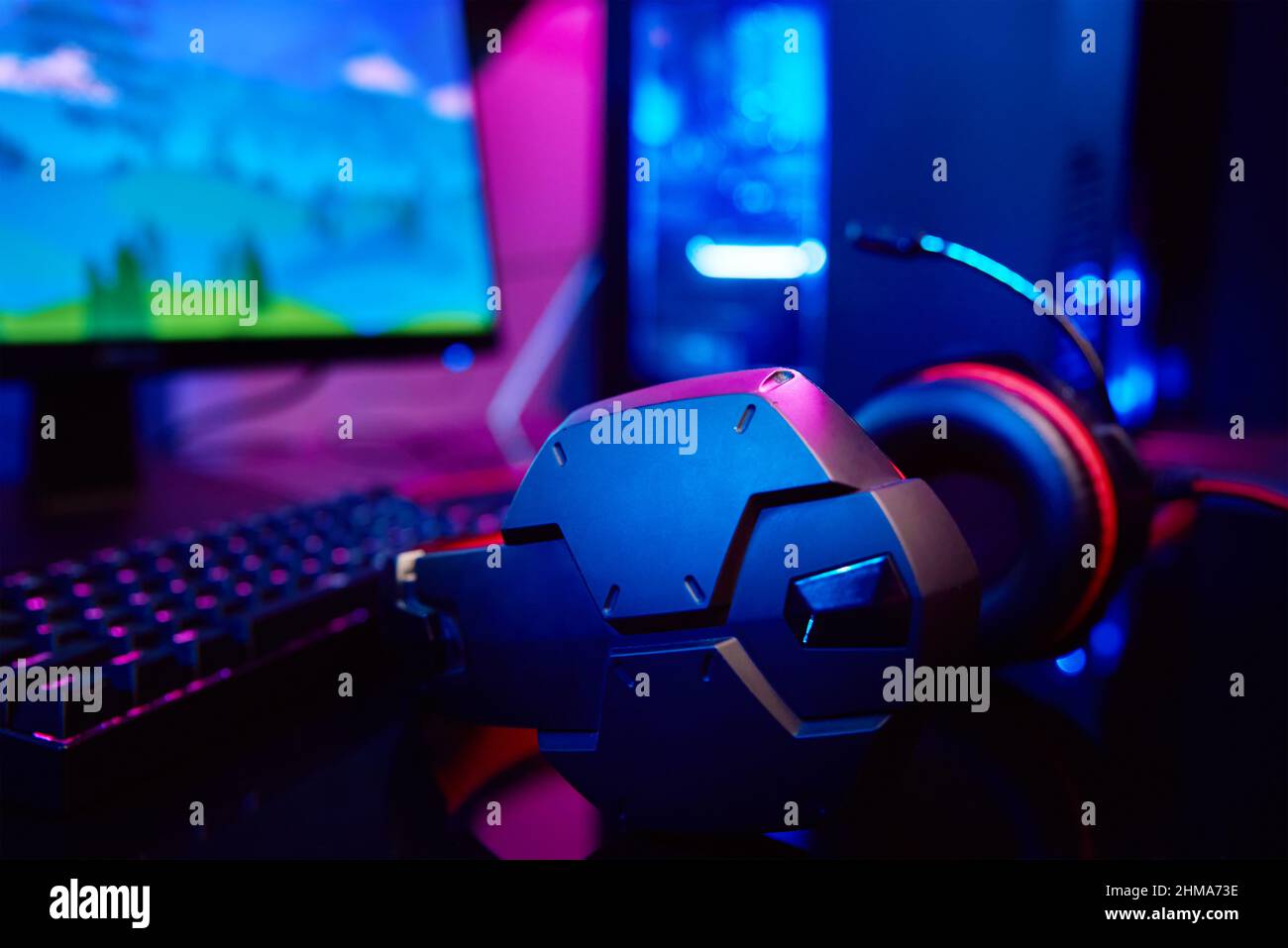 PC with rgb keyboard and headphones for gaming computer video games with neon colored background, dark room with game workplace without people Stock Photo