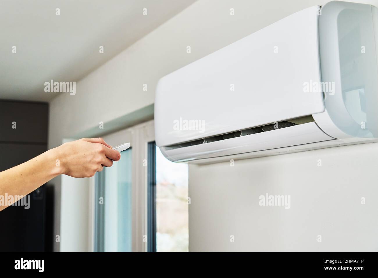 Hand adjusting temperature on air conditioner with remote control, Working air conditioner for