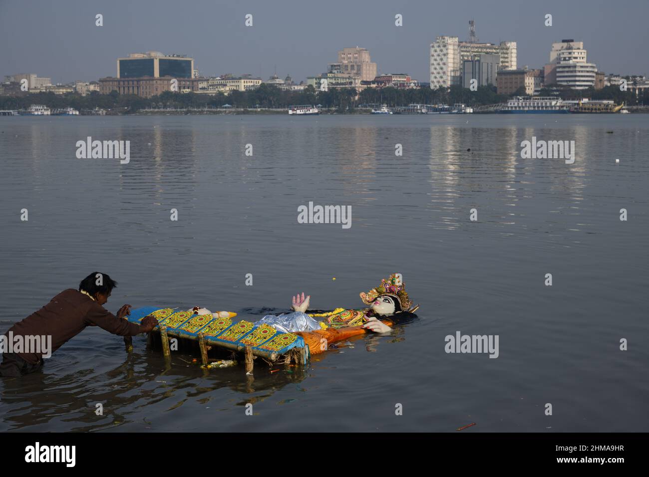 A man floating Hindu goddess Saraswati idol for immersion on the Ganges
