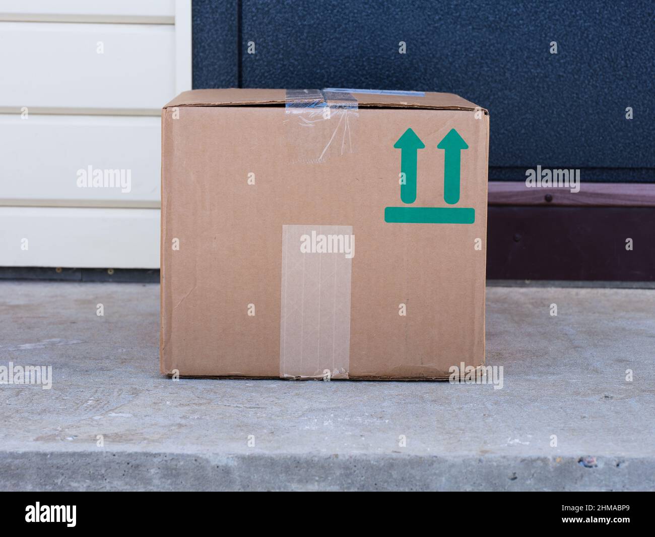 A cardboard box delivered to the house door. Sign This Way Up printed