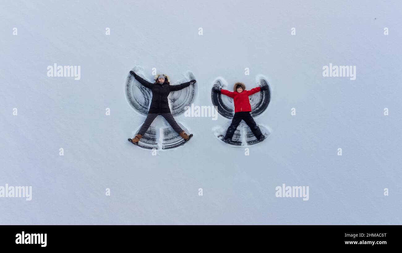 Overhead view of adult and child making snow angels together. Stock Photo