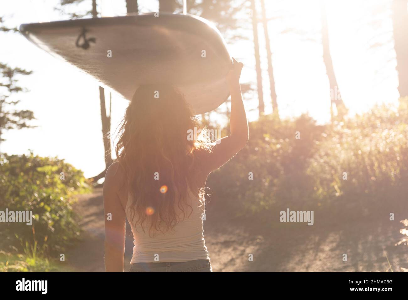 Woman carrying surfboard down trail to the ocean Stock Photo - Alamy