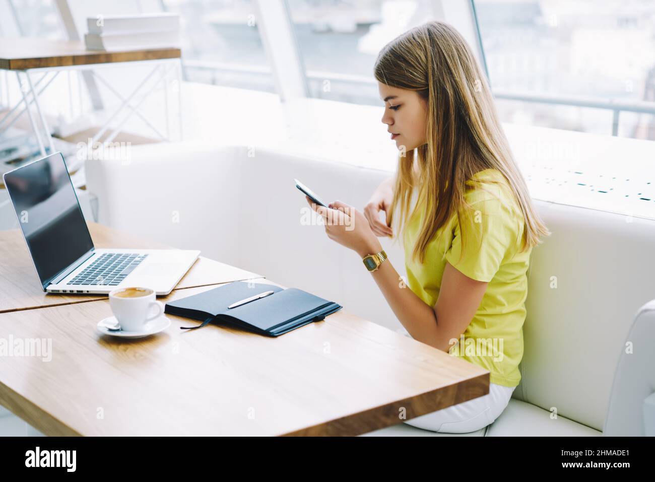 Young woman sending message using mobile phone in office lounge Stock Photo