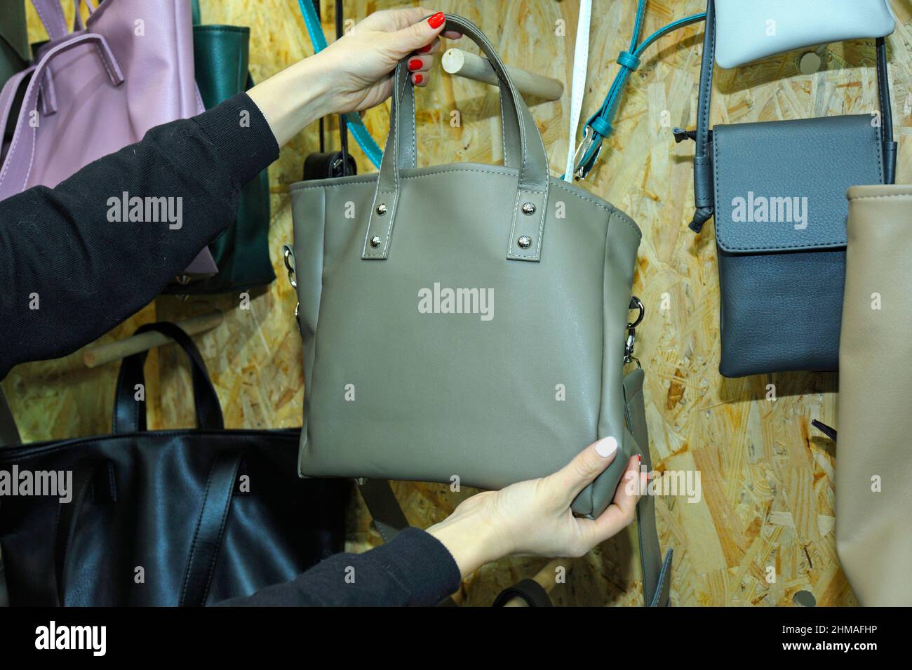 Woman hands seller holding lady bag to hang it on a wall at the boutique  Stock Photo - Alamy
