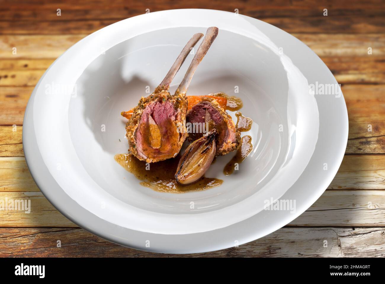 Lamb ribs stuffed with liver baked in the oven with scallions in white plate on wooden table Stock Photo