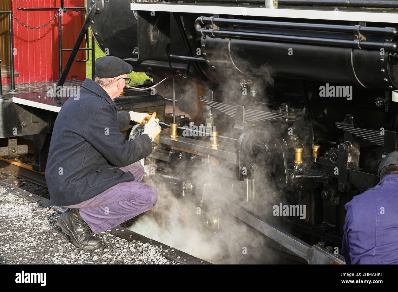 Merthyr Tydfil, Wales - December 2021: Train crew oiling the wheels on a vintage steam engine on the narrow gauge Brecon Mountain Railway Stock Photo