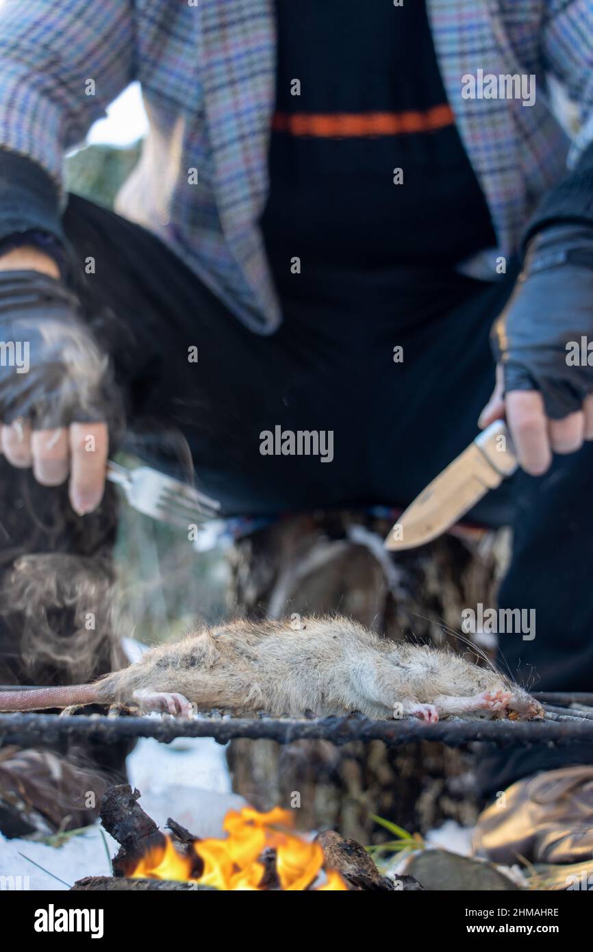 The homeless man grills a rat, close up view. Stock Photo