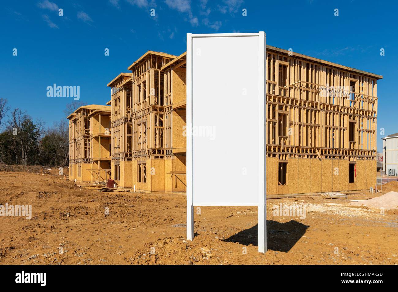 Horizontal shot of new apartment construction framework with a blank white sign in the foreground. Stock Photo