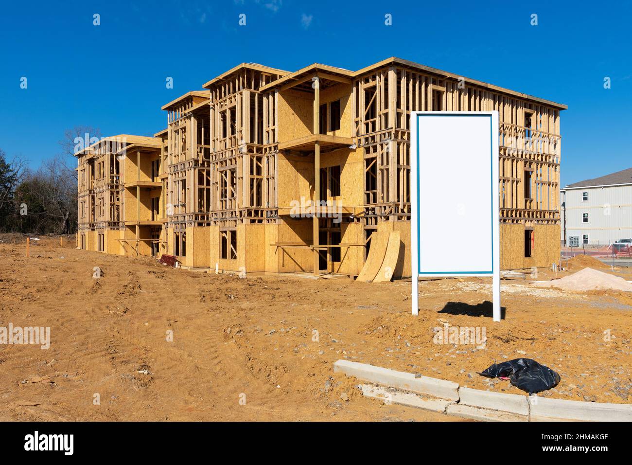 Horizontal shot of a blank white sign in front of a new apartment complex under construction. Stock Photo