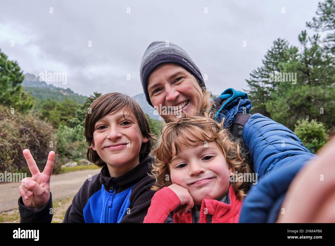 A happy family taking a selfie portrait with smartphone in the mountains in winter Stock Photo