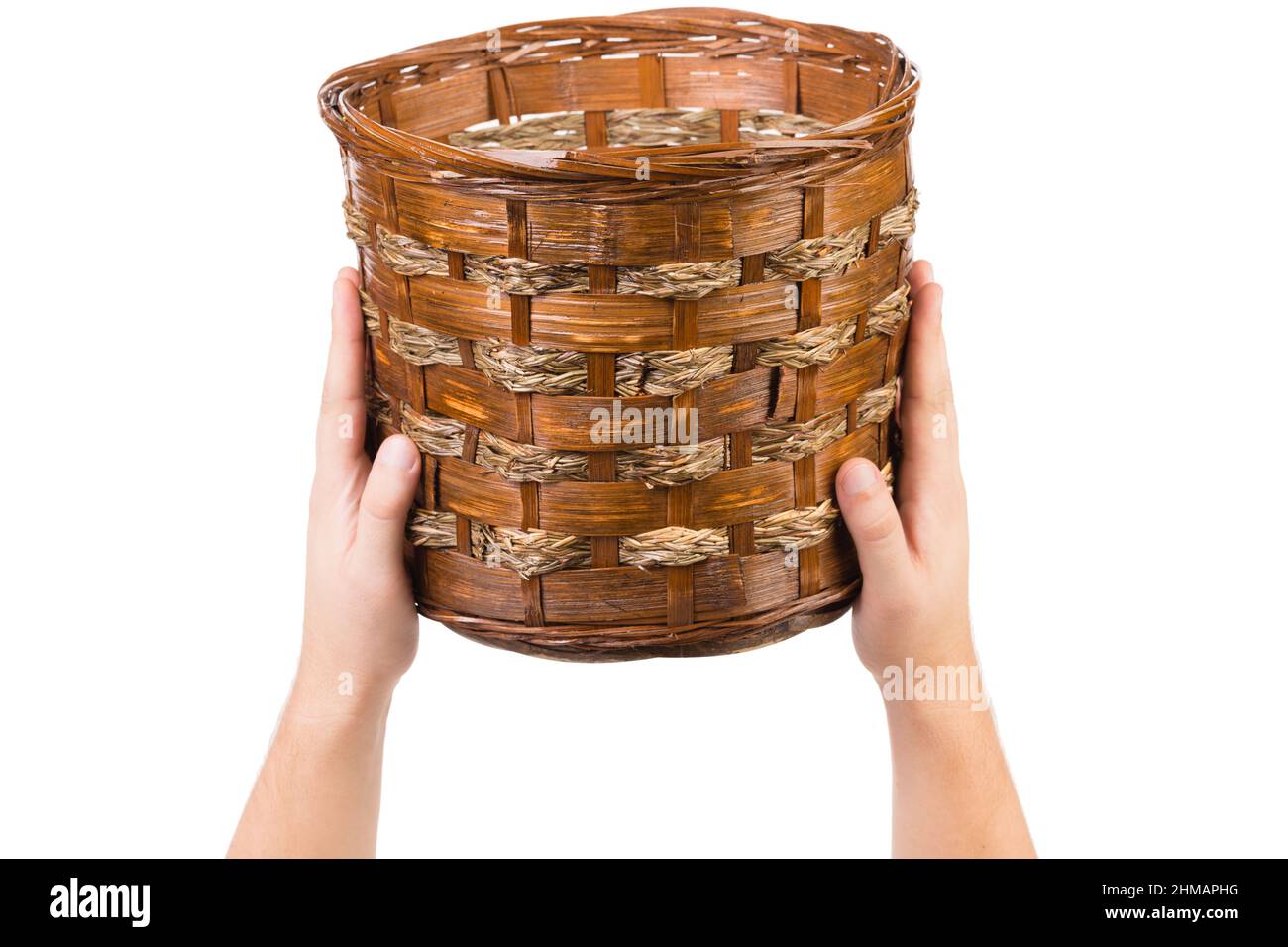 Human hands hold a wicker basket. Wicker basket made of willow branches