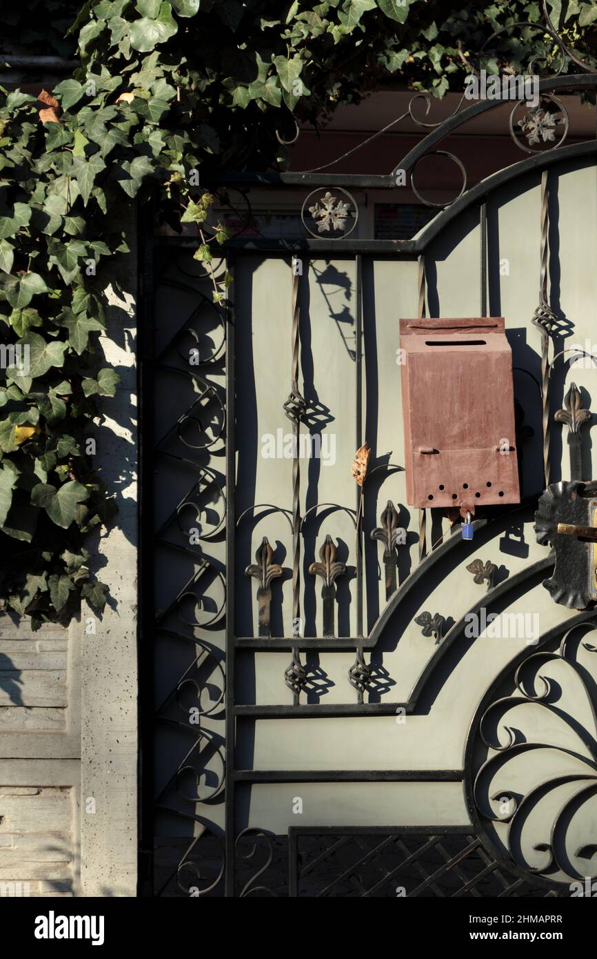 A gate with a wrought iron door and a letterbox. Close-up. Stock Photo