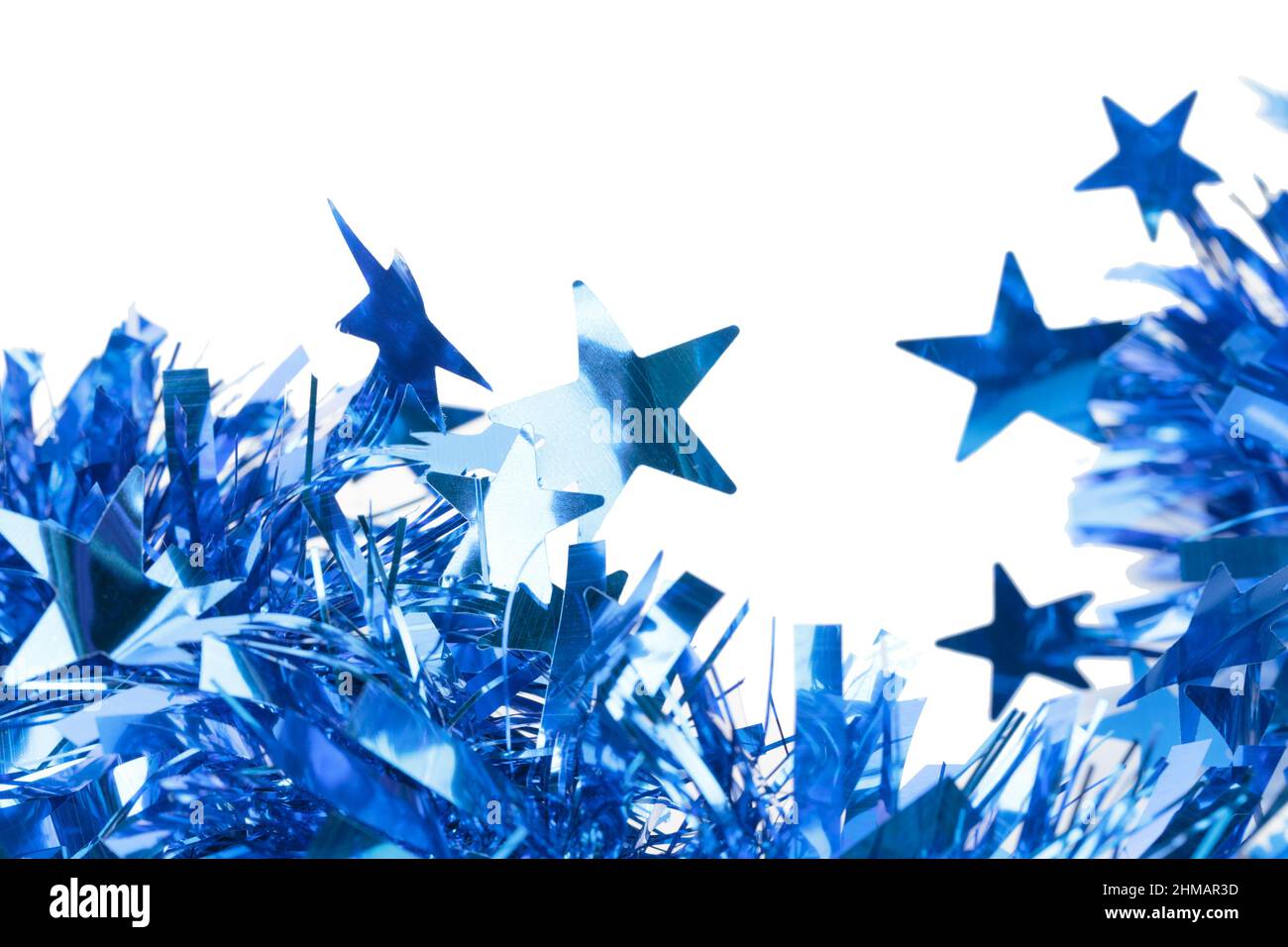 Blue Christmas tinsel with stars. It is located on a white surface. Close-up. Stock Photo