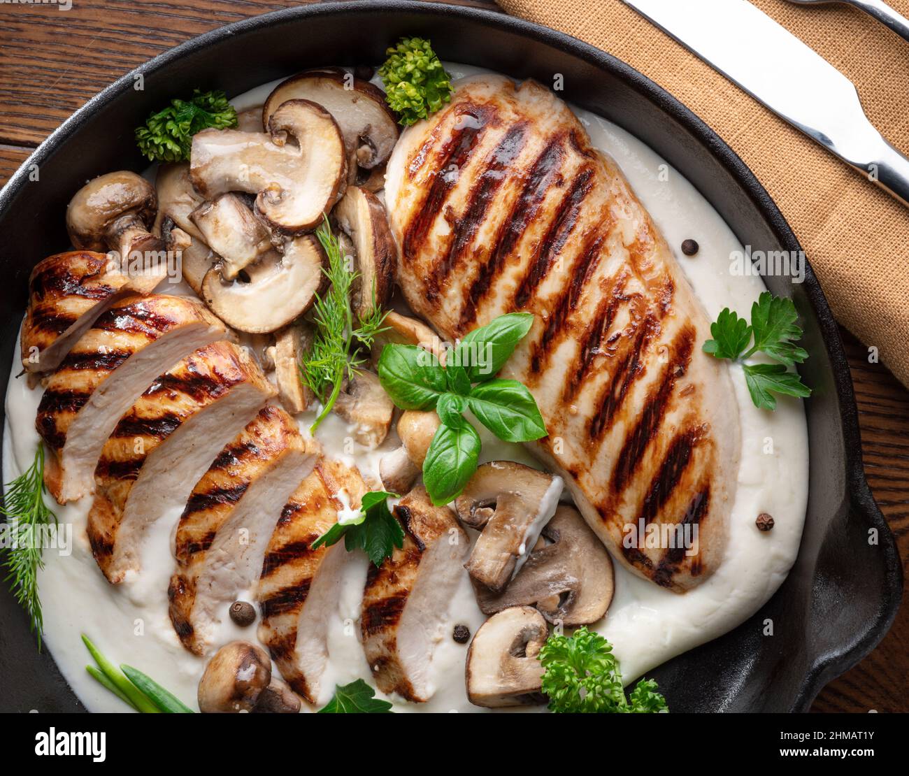 Roasted chicken fillet and mushrooms with herb in the frying pan on the wooden table close-up. Stock Photo