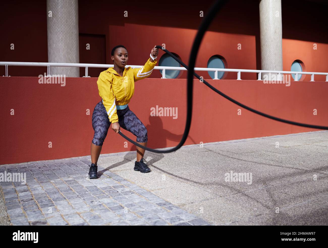 Turning pain into power. Shot of a young woman using battle ropes against an urban background. Stock Photo