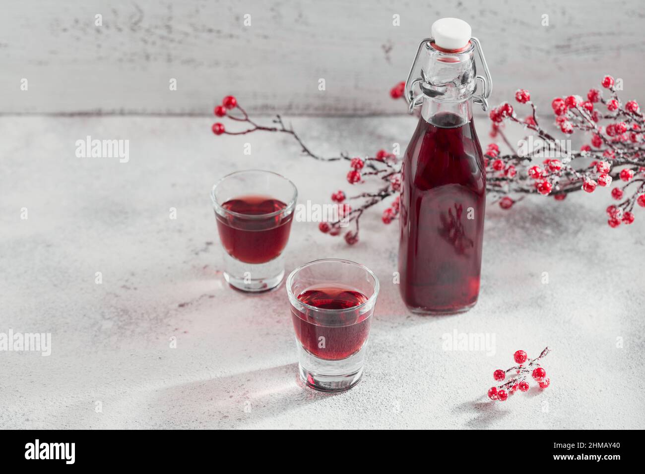 Homemade infused vodka, tincture or liqueur of red cherry on white background. Berry alcoholic drinks concept. Stock Photo