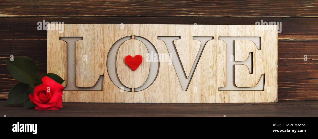 Love word written on wooden background and red rose Stock Photo