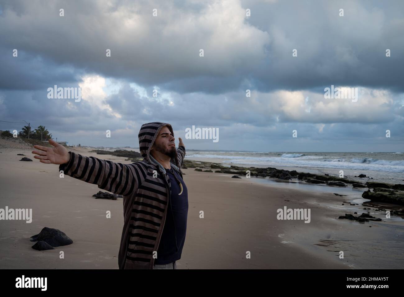 Happy man on the beach. Positive attitude of a young man at sunrise. Stock Photo