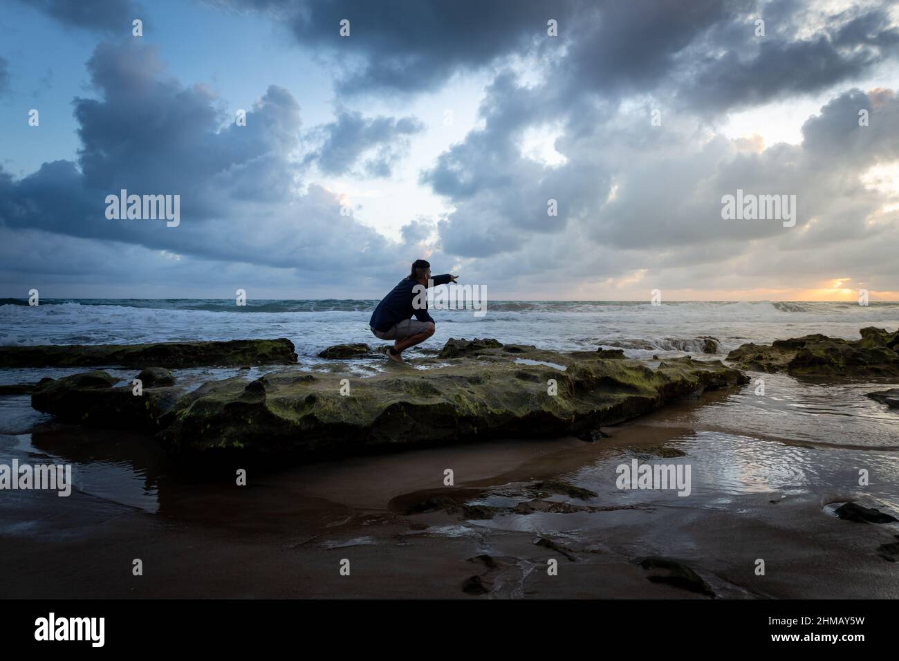 Happy man on the beach. Positive attitude of a young man at sunrise. Stock Photo