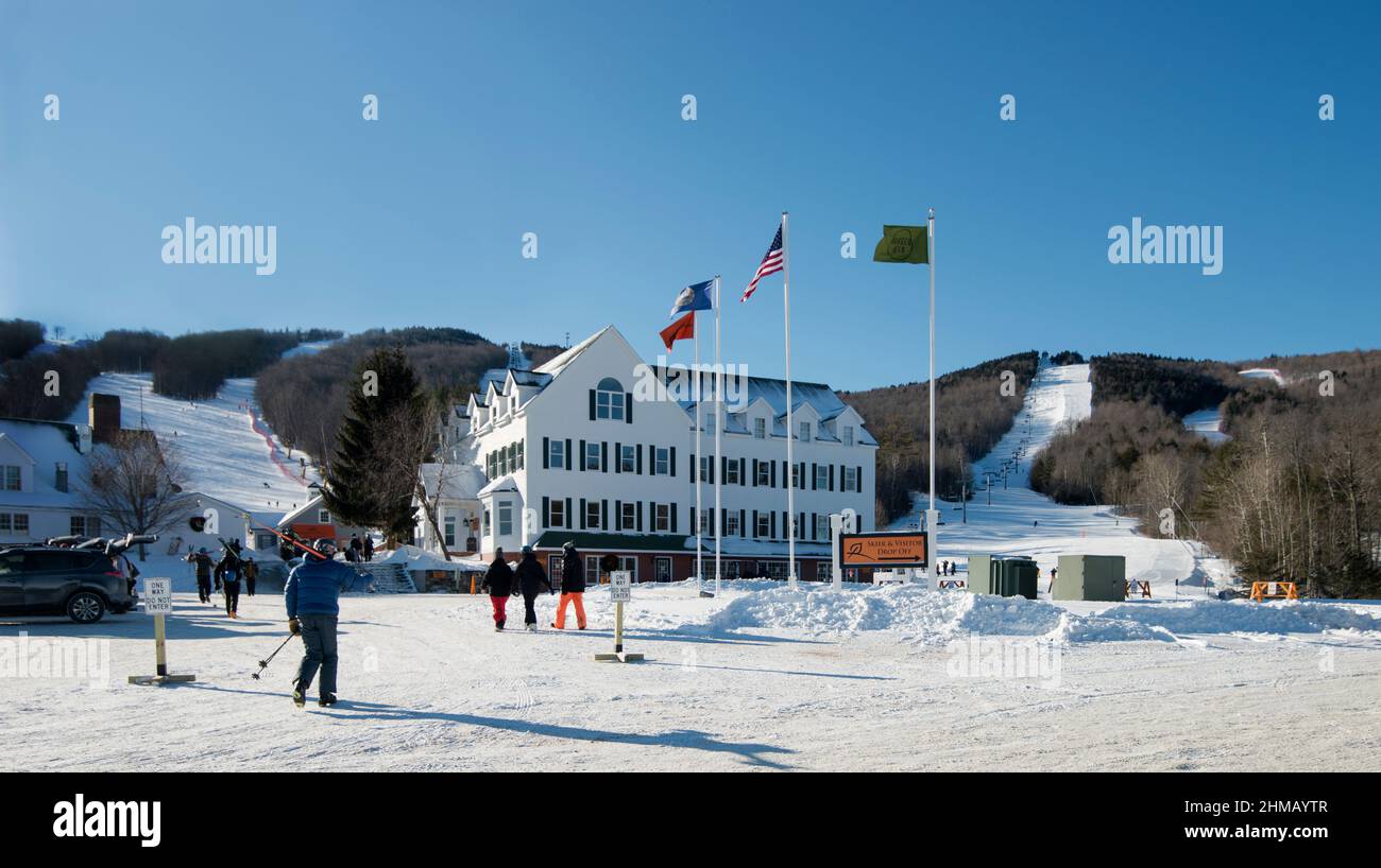 Morning at Ragged Mountain Ski Resort in Danbury, New Hampshire, USA. Skiers walking from the parking lot toward the Meeting House Lodge. Stock Photo