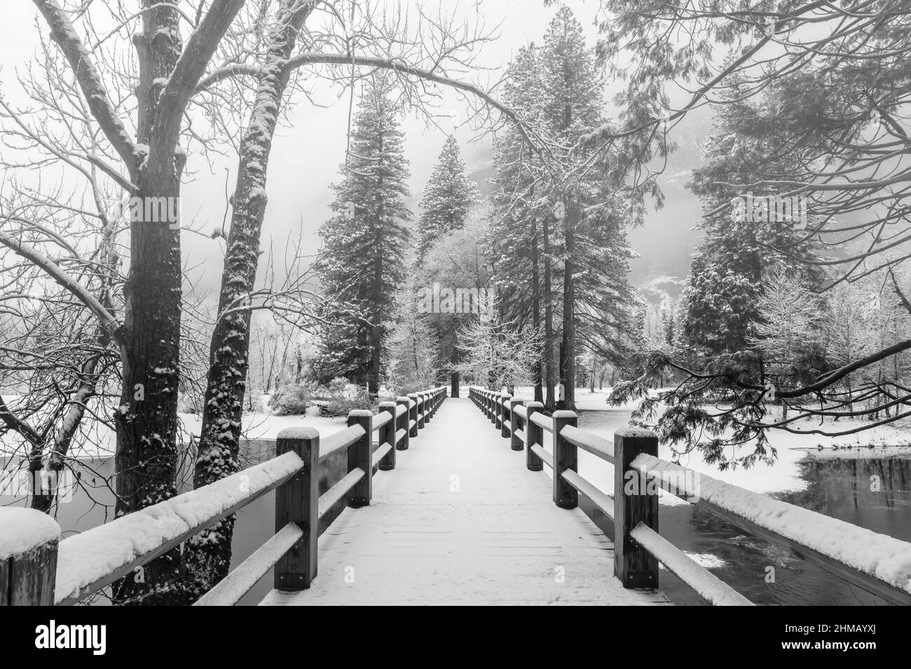 Fresh new snow blanket the bridge over  Merced River after an early winter storm in Yosemite National Park, California, USA. Stock Photo