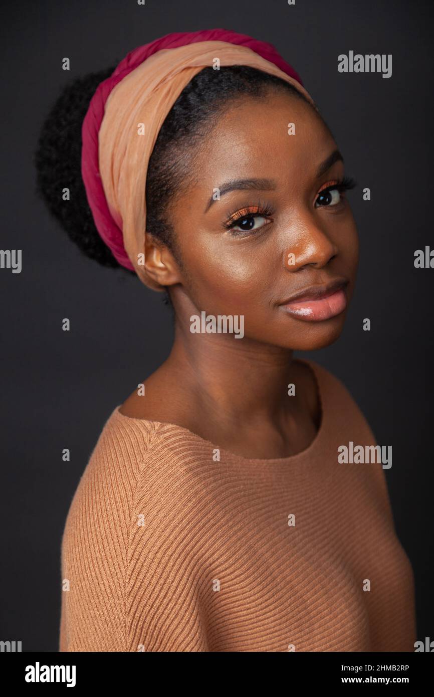 A close up portrait of a black woman with her hair tied back and wearing and hair band. Stock Photo