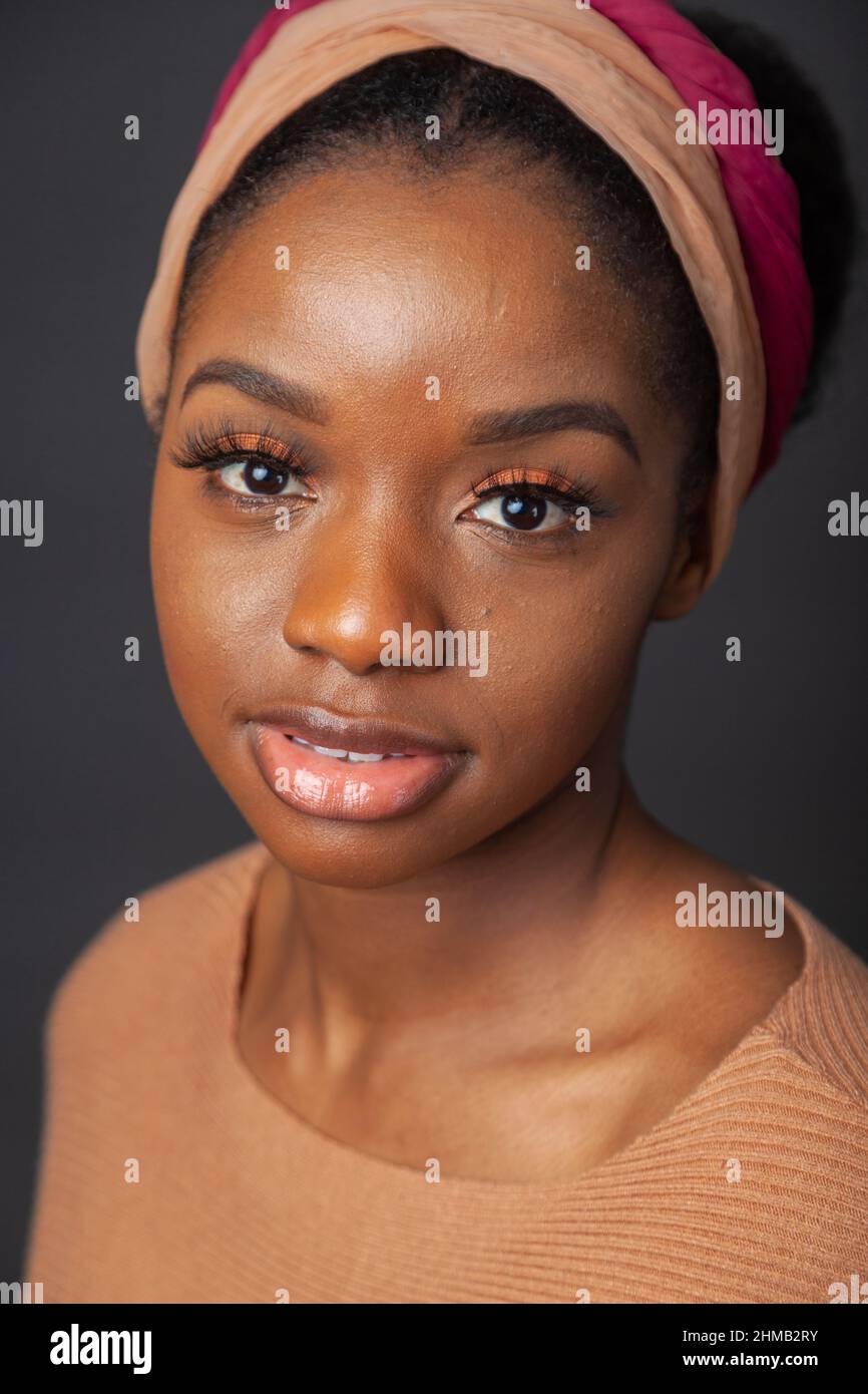 A close up portrait of a black woman with her hair tied back and wearing and hair band. Stock Photo