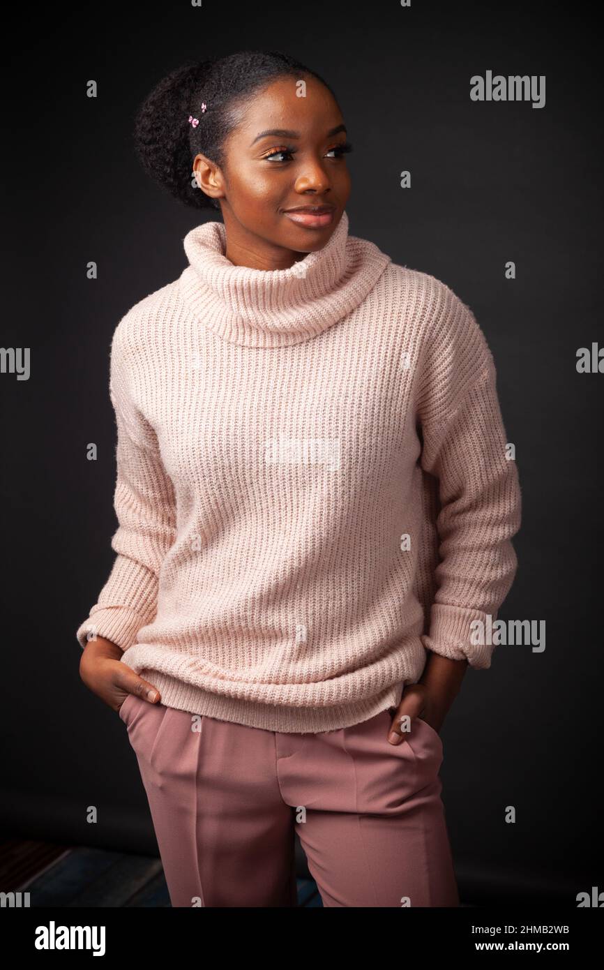 A cool young black woman wearing a turtleneck sweater with her hands in her pockets Stock Photo