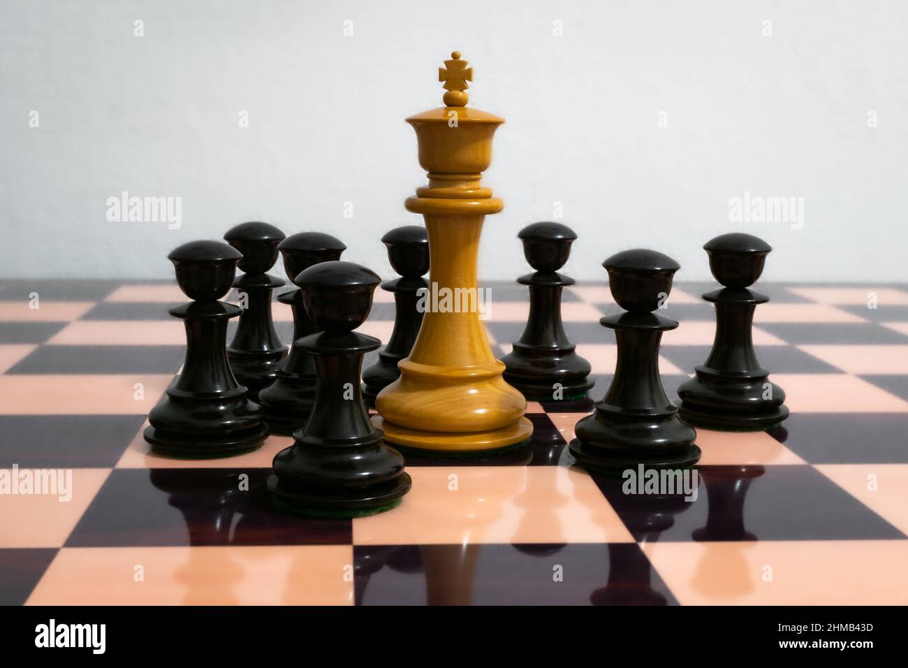 White chess king surrounded by black pawns Stock Photo