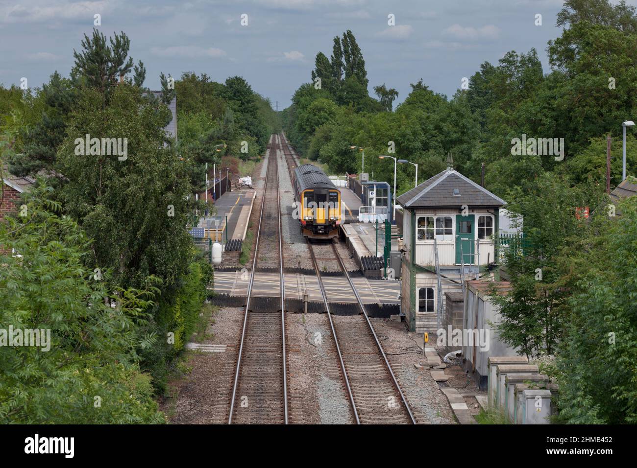 East Midlands trains class 156 sprinter train 156405 at Lowdham railway station (East of Nottingham)  with the level crossing and closed signal box Stock Photo