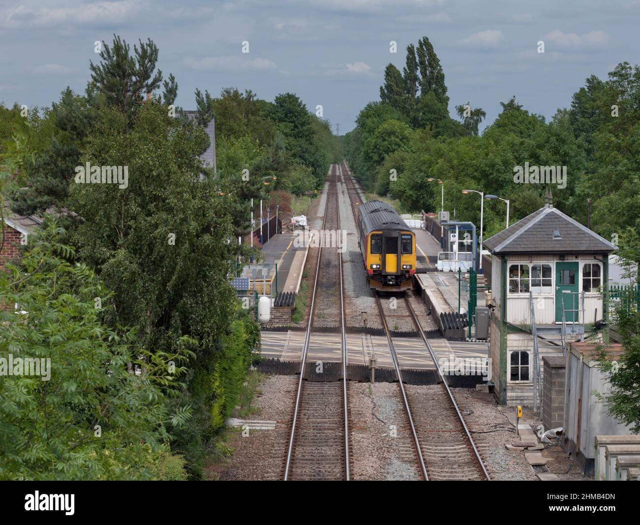 East Midlands trains class 156 sprinter train 156405 at Lowdham railway station (East of Nottingham)  with the level crossing and closed signal box Stock Photo
