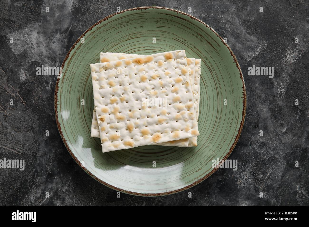 Plate with Jewish flatbread for Passover on dark background Stock Photo