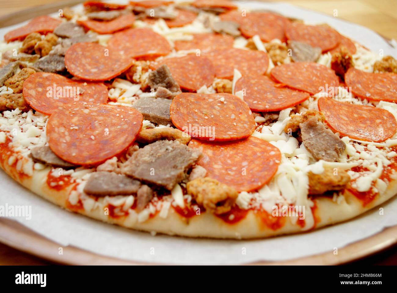 Perfect raw meat lovers pizza ready for the oven hires stock