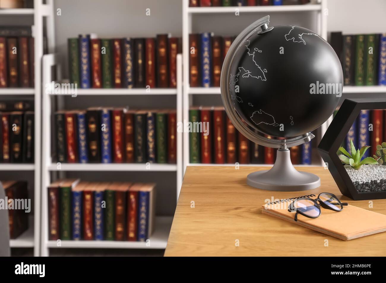 Globe and eyeglasses on table in home library Stock Photo