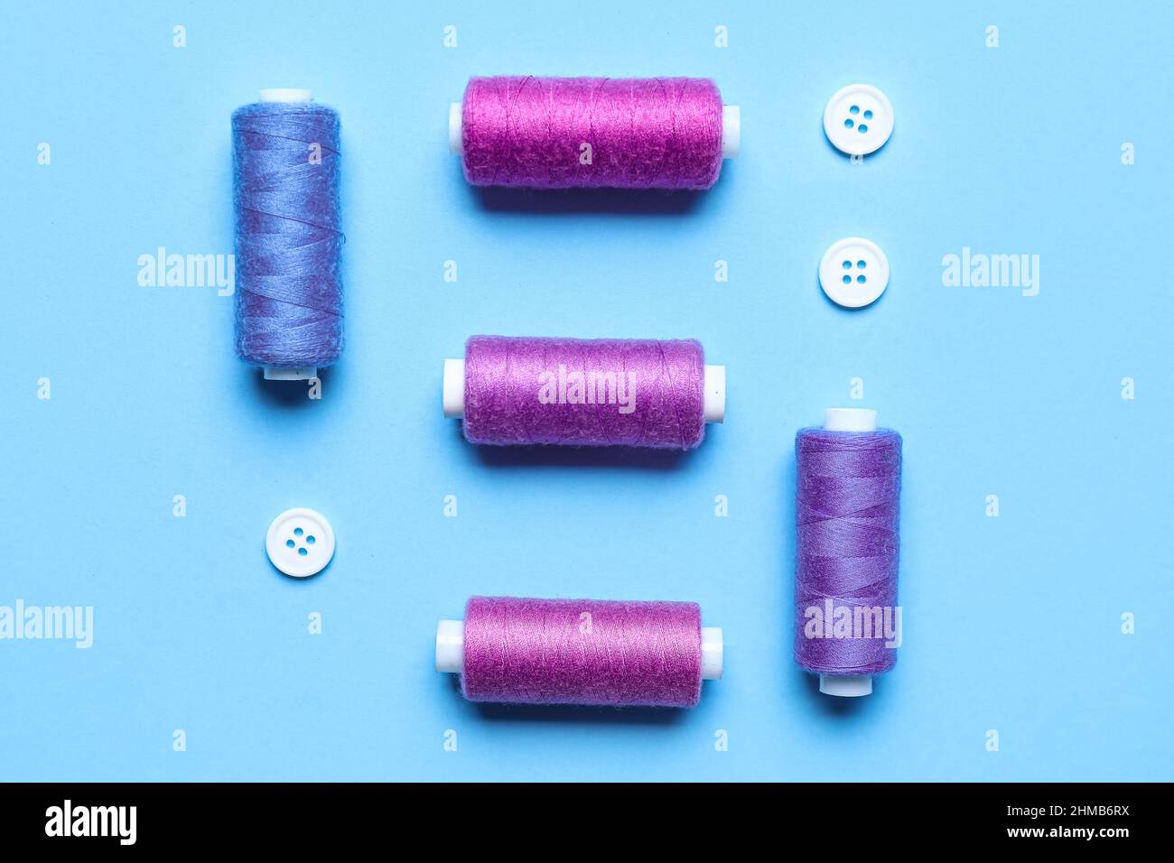Different sewing threads with buttons on blue background Stock Photo