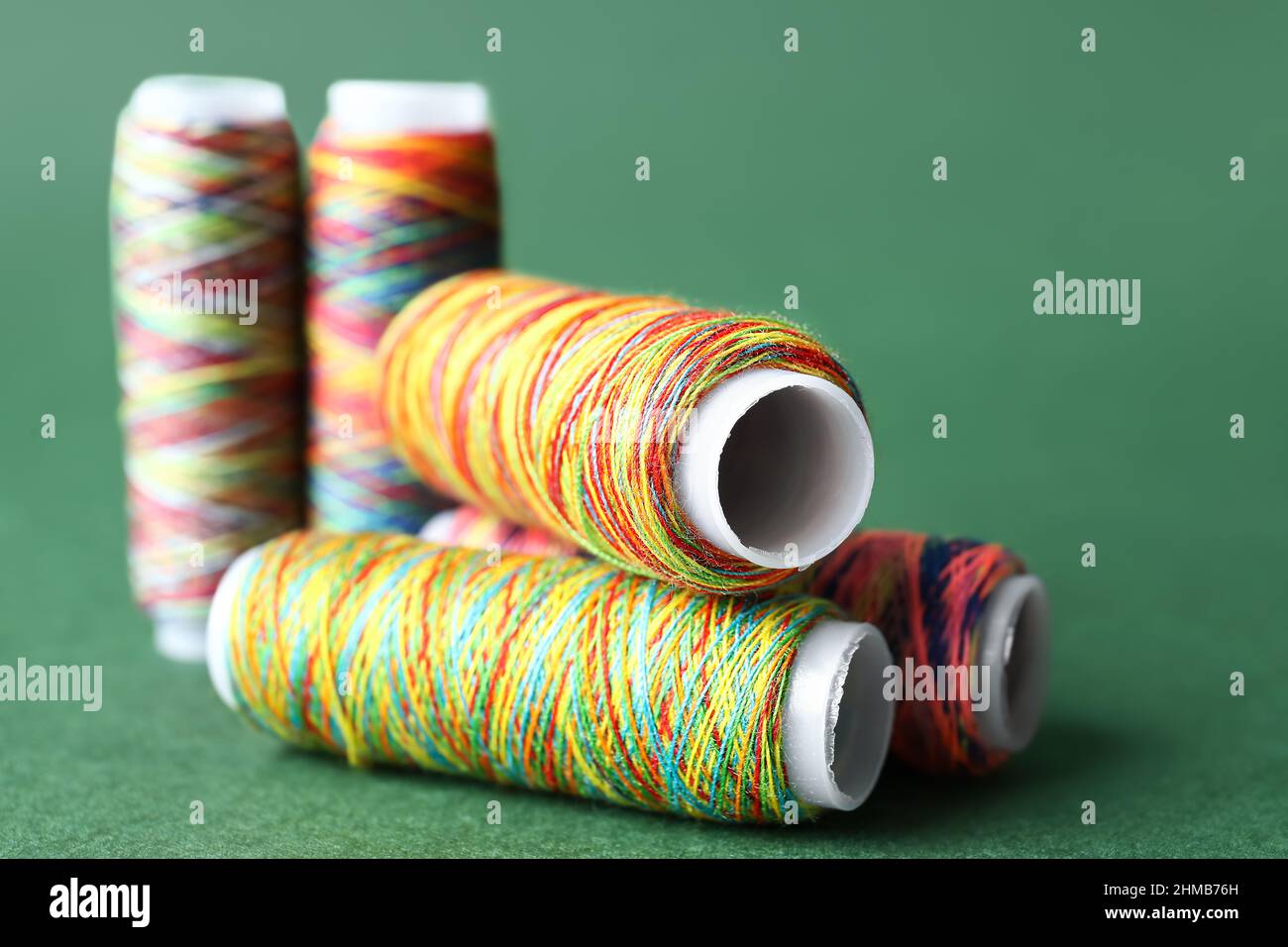 Rainbow sewing thread spools on color background Stock Photo - Alamy