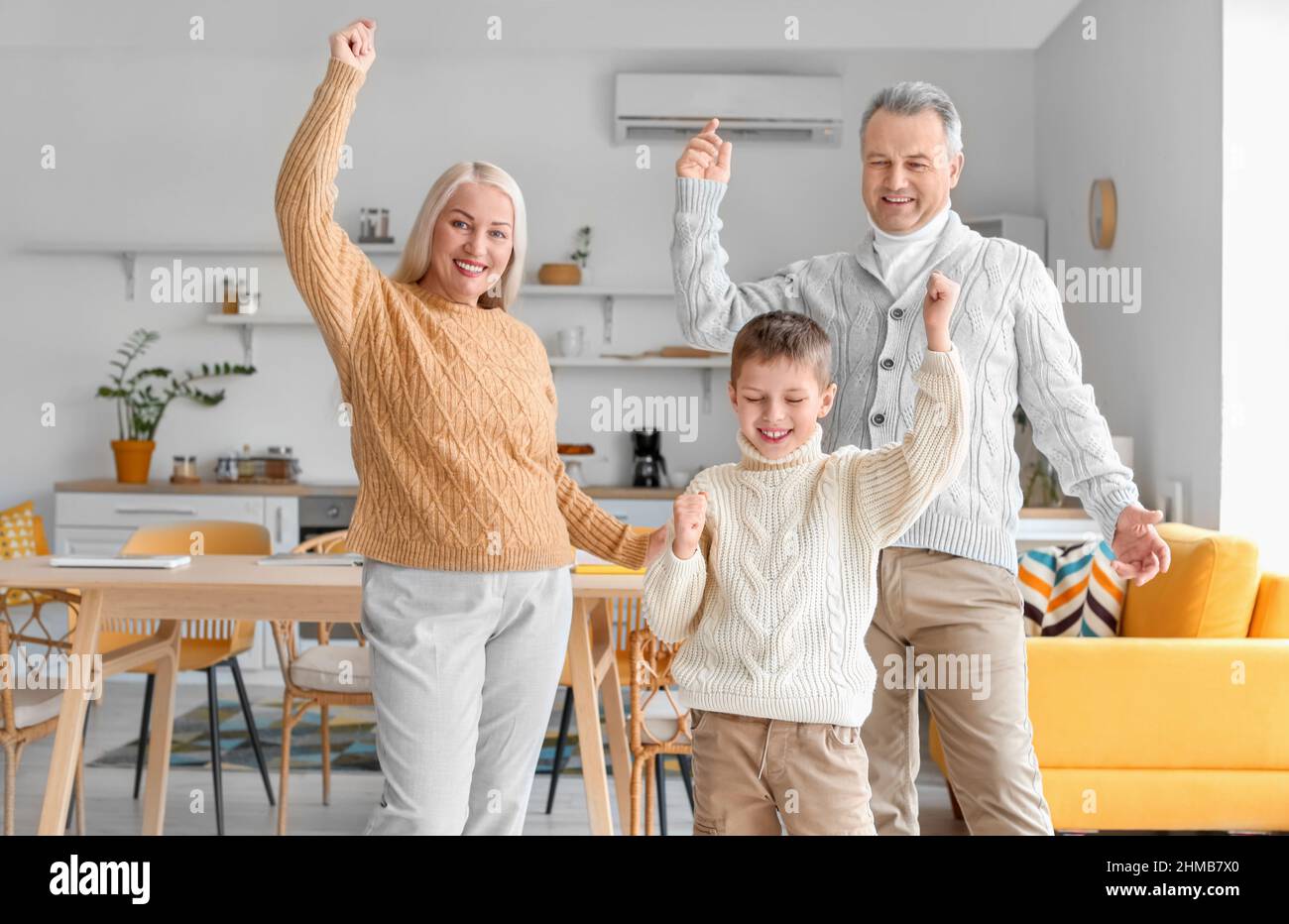 Little boy with his grandparents in warm sweaters dancing at home Stock Photo