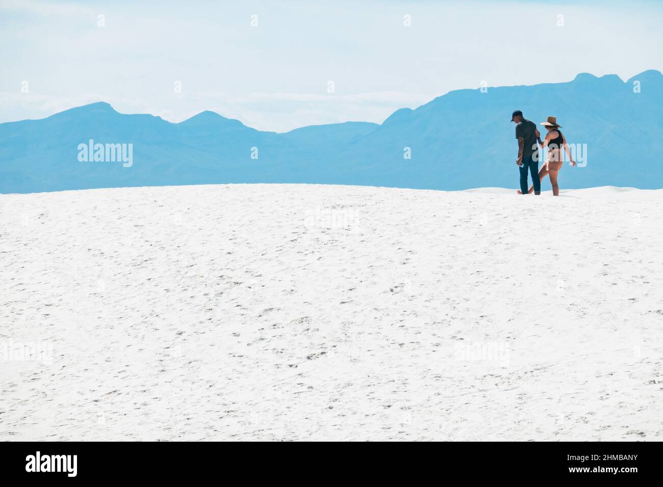 A young couple play on top of sand dunes at White Sands National Park, New Mexico, United States Stock Photo
