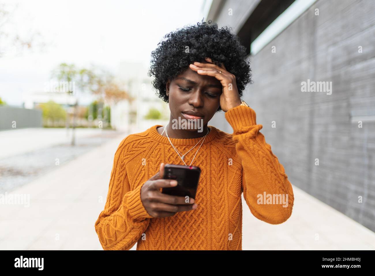 Black woman looking worried while reading something on the mobile phone. Stock Photo